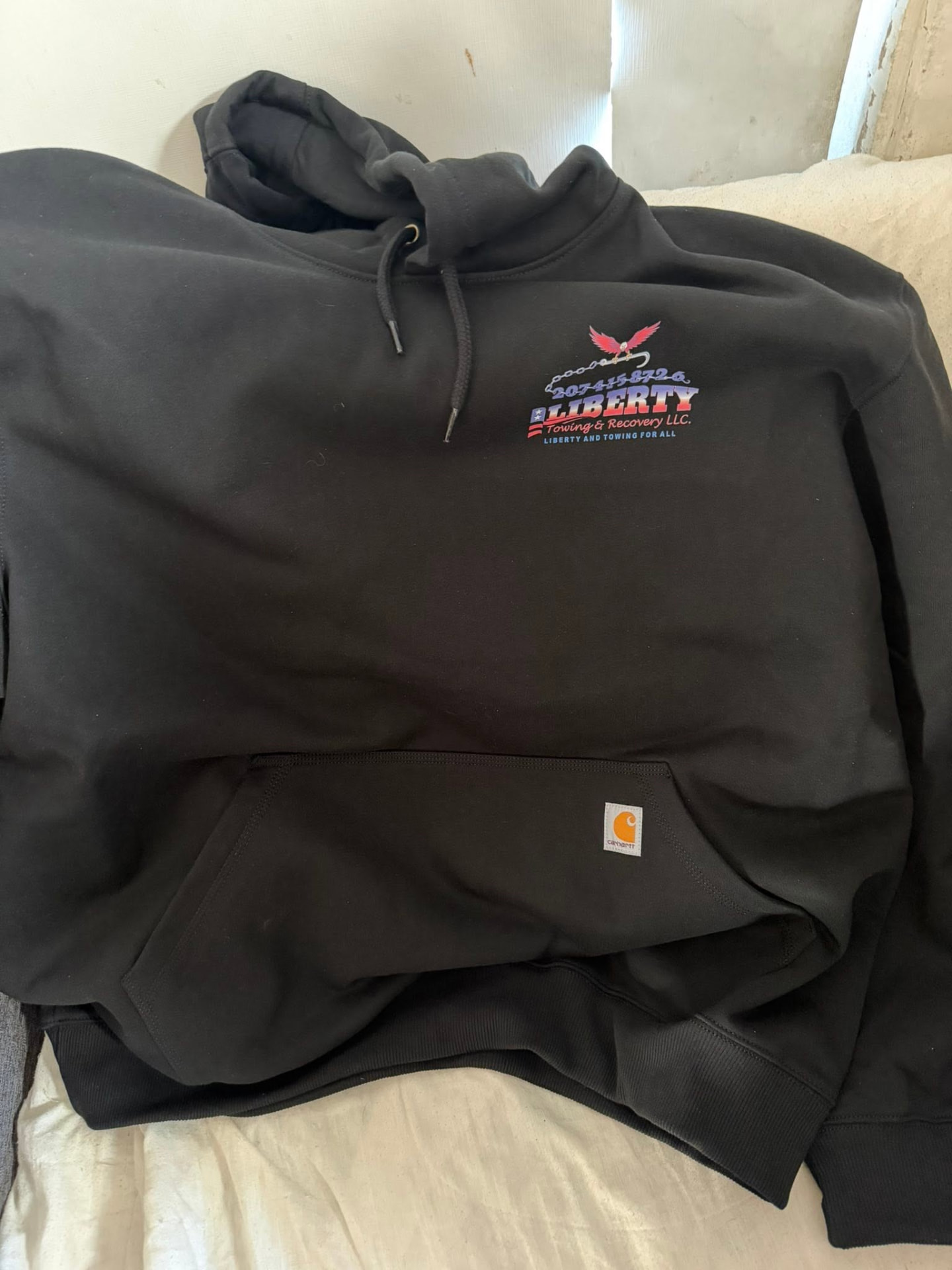 Front of a dark Carhartt hoodie with the Liberty chest logo