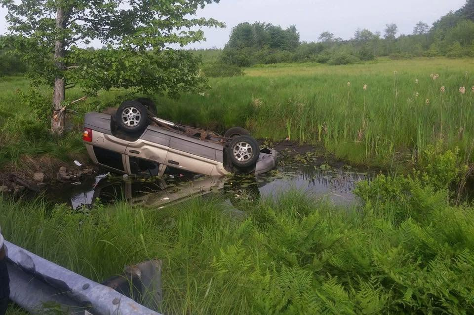 Overturned vehicle in a water-filled ditch awaiting recovery